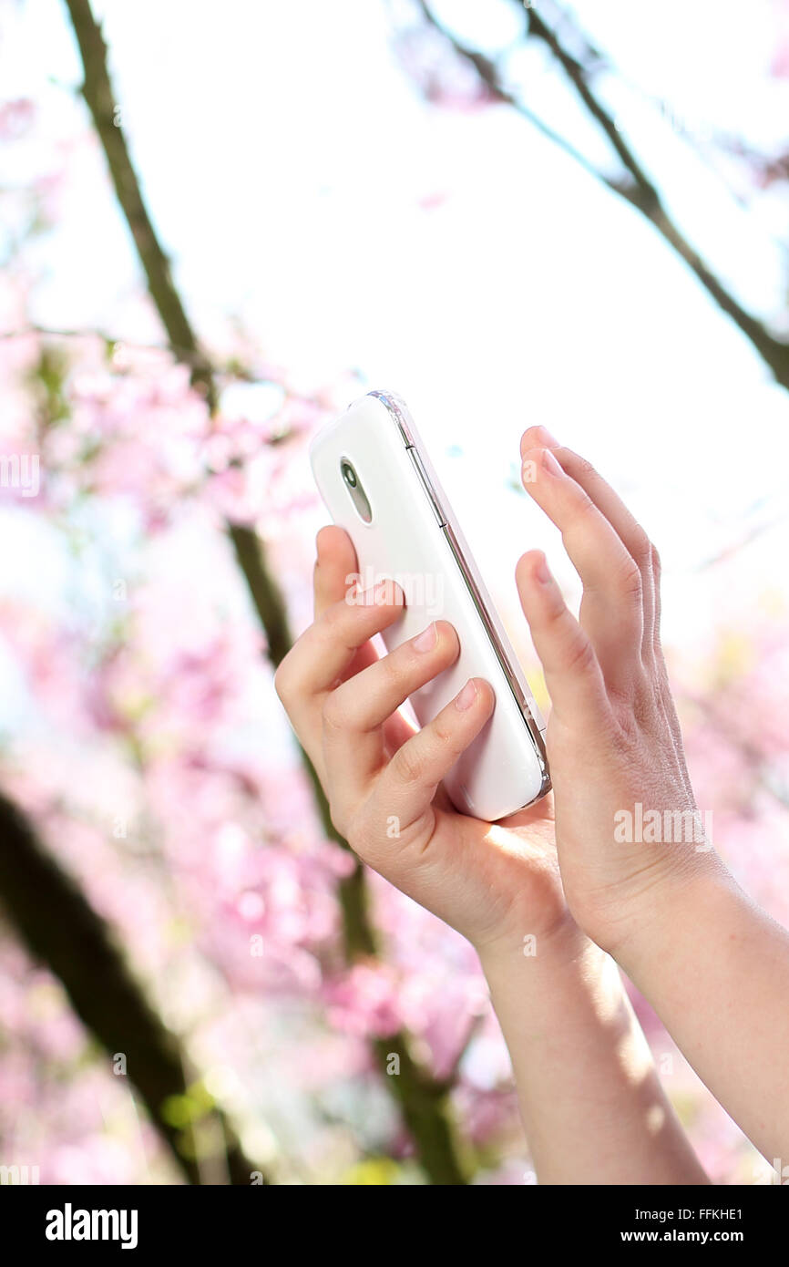 The child's hands writing a text message on your smartphone . Girl with mobile phone. The child sends sms. Stock Photo