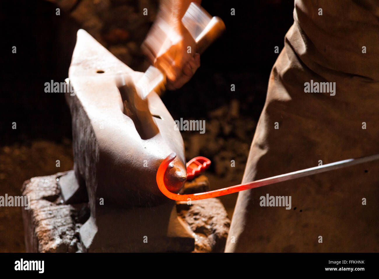 Blacksmith forging steel with hammer and anvil Stock Photo
