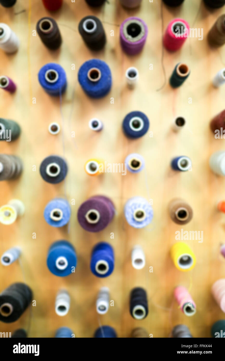 Blurry background of a large group of displayed bobbins of thread. Stock Photo