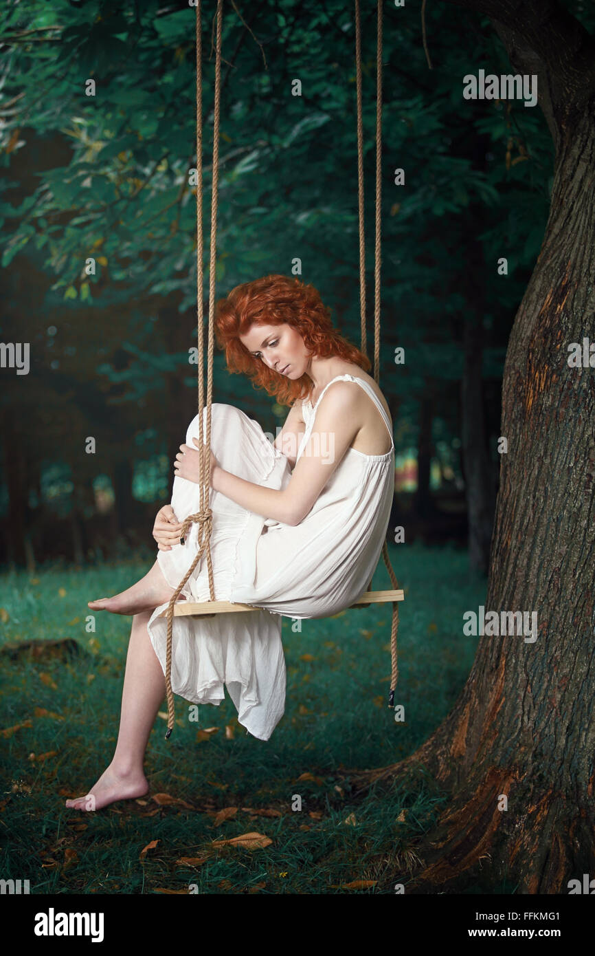 Beautiful thoughtful woman on a swing in the wood . Romantic and vintage portrait Stock Photo