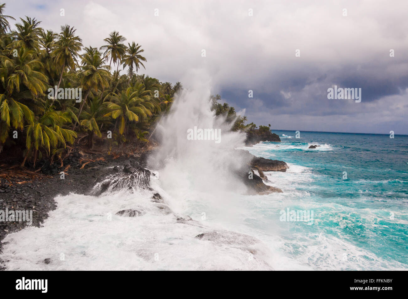 Big waves crushing on the shore of a tropical island with palm trees during a storm. Praia Piscina - Sao Tomè and Principe. Stock Photo