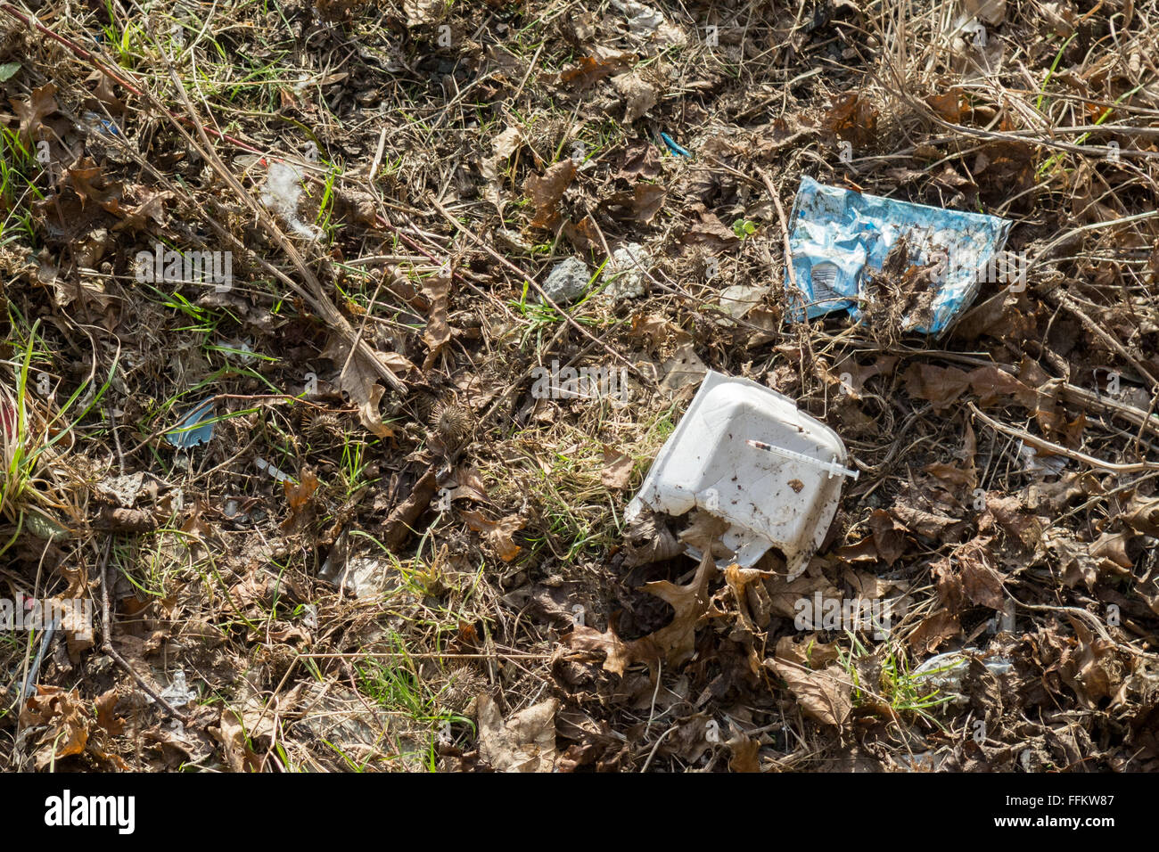 Used needle stuck in empty fast food packaging discarded by River Clyde, Glasgow, Scotland, UK Stock Photo