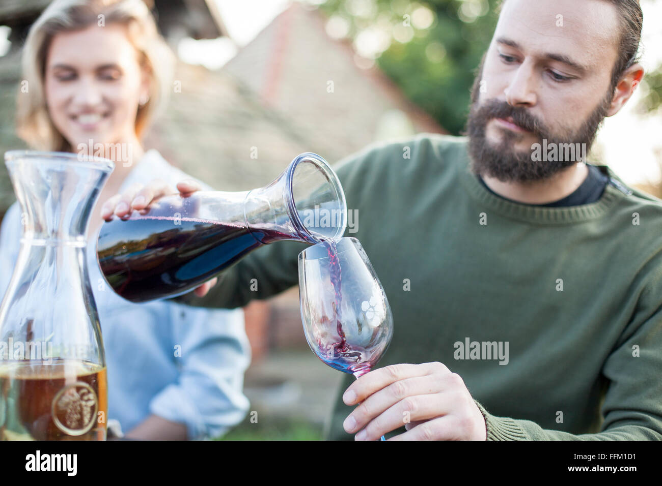 Man pouring red wine on garden party Stock Photo