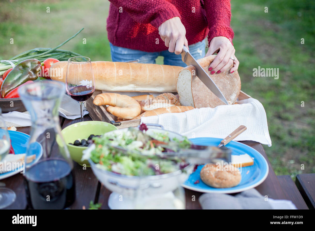 Person on garden party slicing loaf of bread Stock Photo