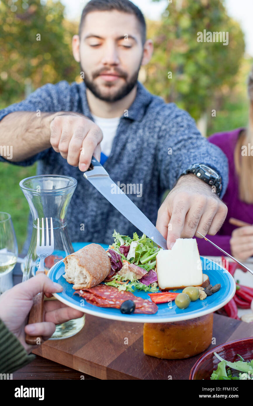 Man cutting cheese on garden party Stock Photo