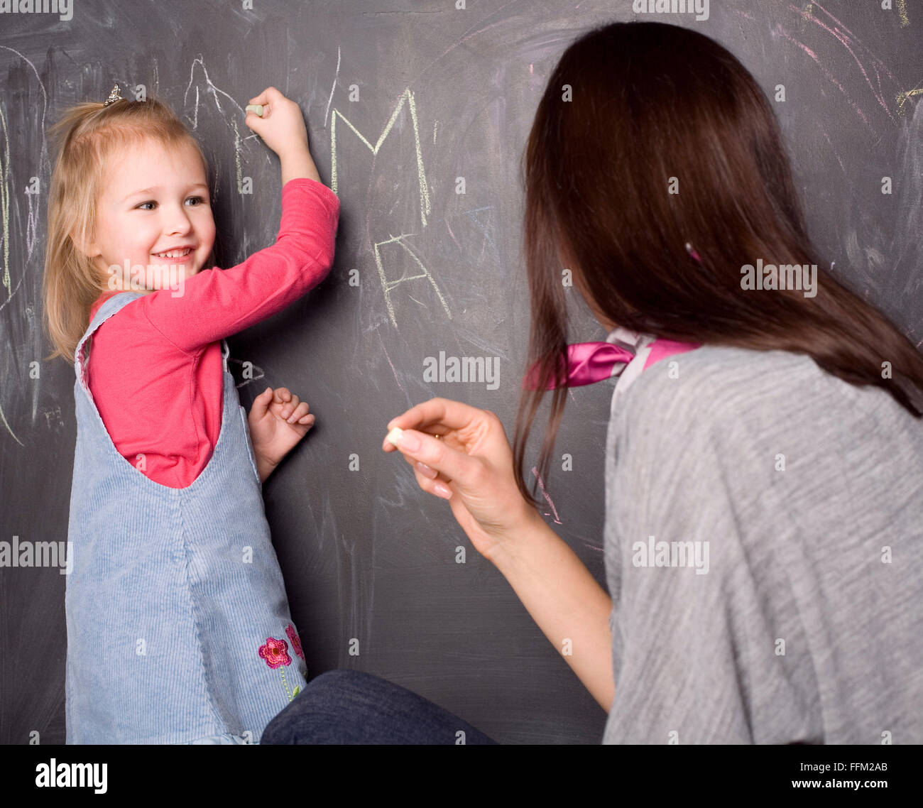 little cute pupil girl with teacher in classroom writing on blackboard  Stock Photo - Alamy