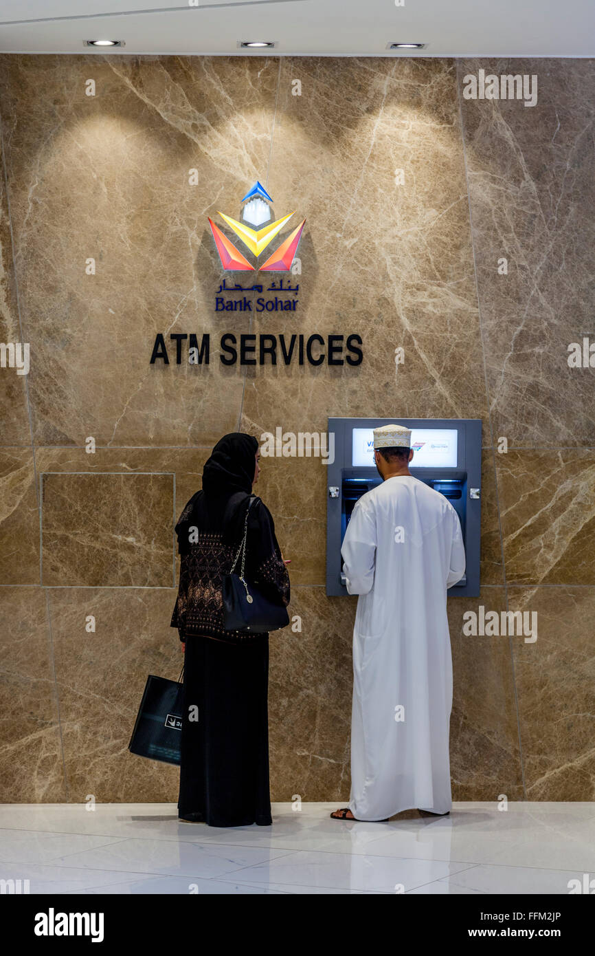 An Omani Couple At An ATM Machine In The Oman Avenues Shopping Mall, Muscat, Sultanate Of Oman Stock Photo