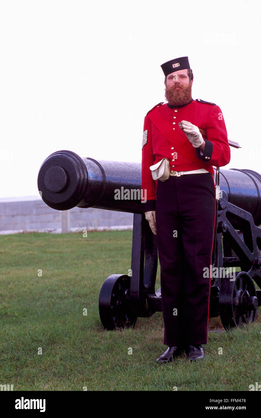 Fort Henry National Historic Site, Kingston, Ontario, Canada - British Soldier Reenactor standing at Attention beside Cannon Stock Photo