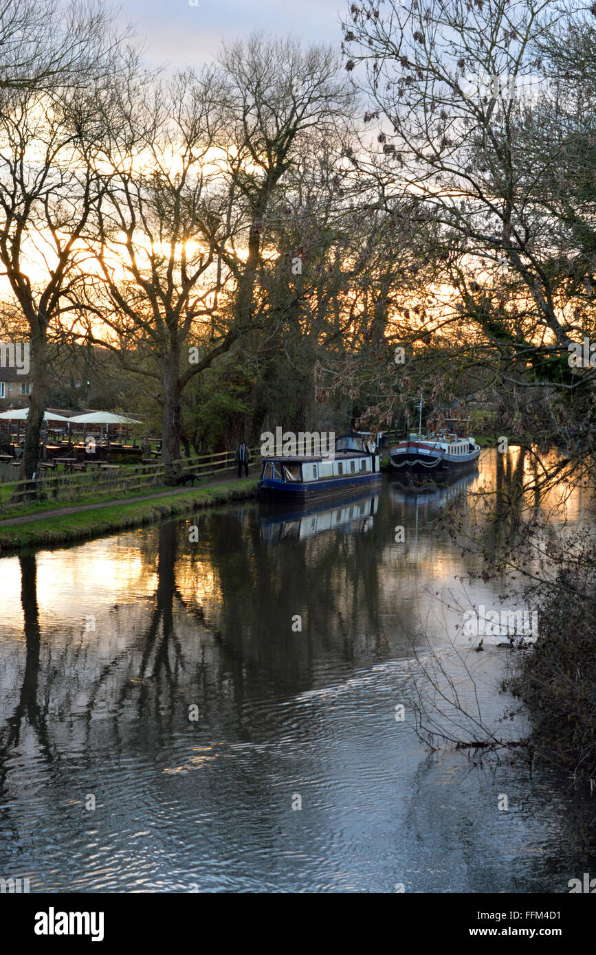 Canal flowing with a beautiful sunset behind the Cunning Man, Burghfield, Reading, Berkshire, UK. Charles Dye / Alamy Live News Stock Photo