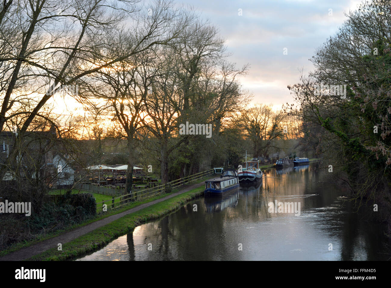 Canal flowing with a beautiful sunset behind the Cunning Man, Burghfield, Reading, Berkshire, UK. Charles Dye / Alamy Live News Stock Photo