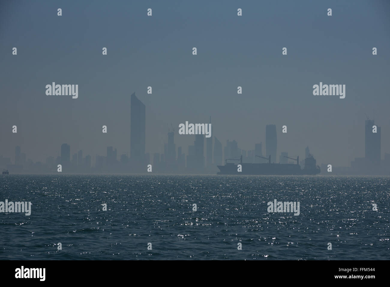 A cargo ship is silhouetted against a cityscape Stock Photo