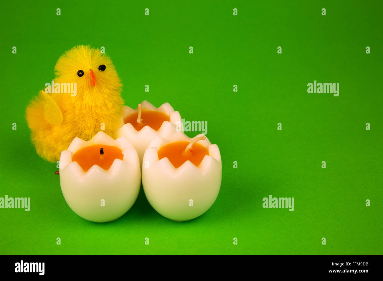 Three easter candle i shape half of eggs and two gigurines yellow chicken on isolated green , easter decoration. Stock Photo