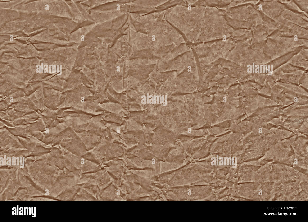 A sheet of brown grainy clear creased parchment paper, interesting background and texture. Horizontal view. Stock Photo