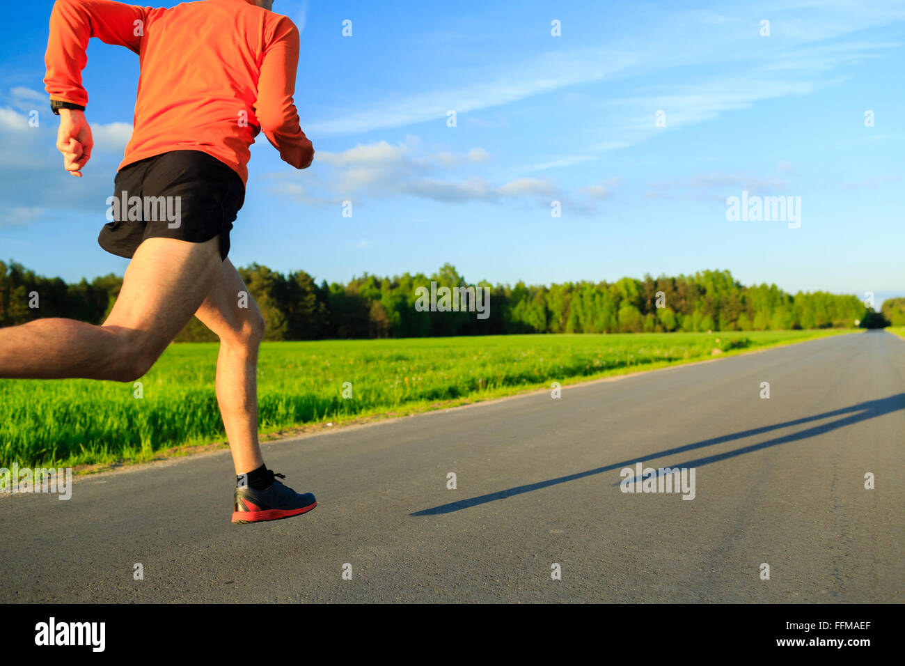 Man runner running on country road, training inspiration and motivation in summer sunset. Young athlete male healthy training Stock Photo