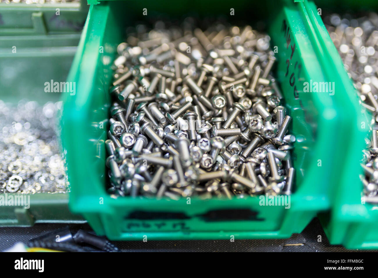 screws in a green box in an electronics factory Stock Photo