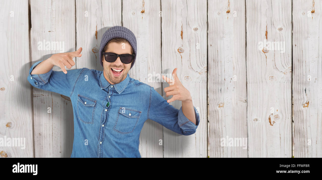 Composite image of happy hipster showing rock and roll hand sign Stock Photo