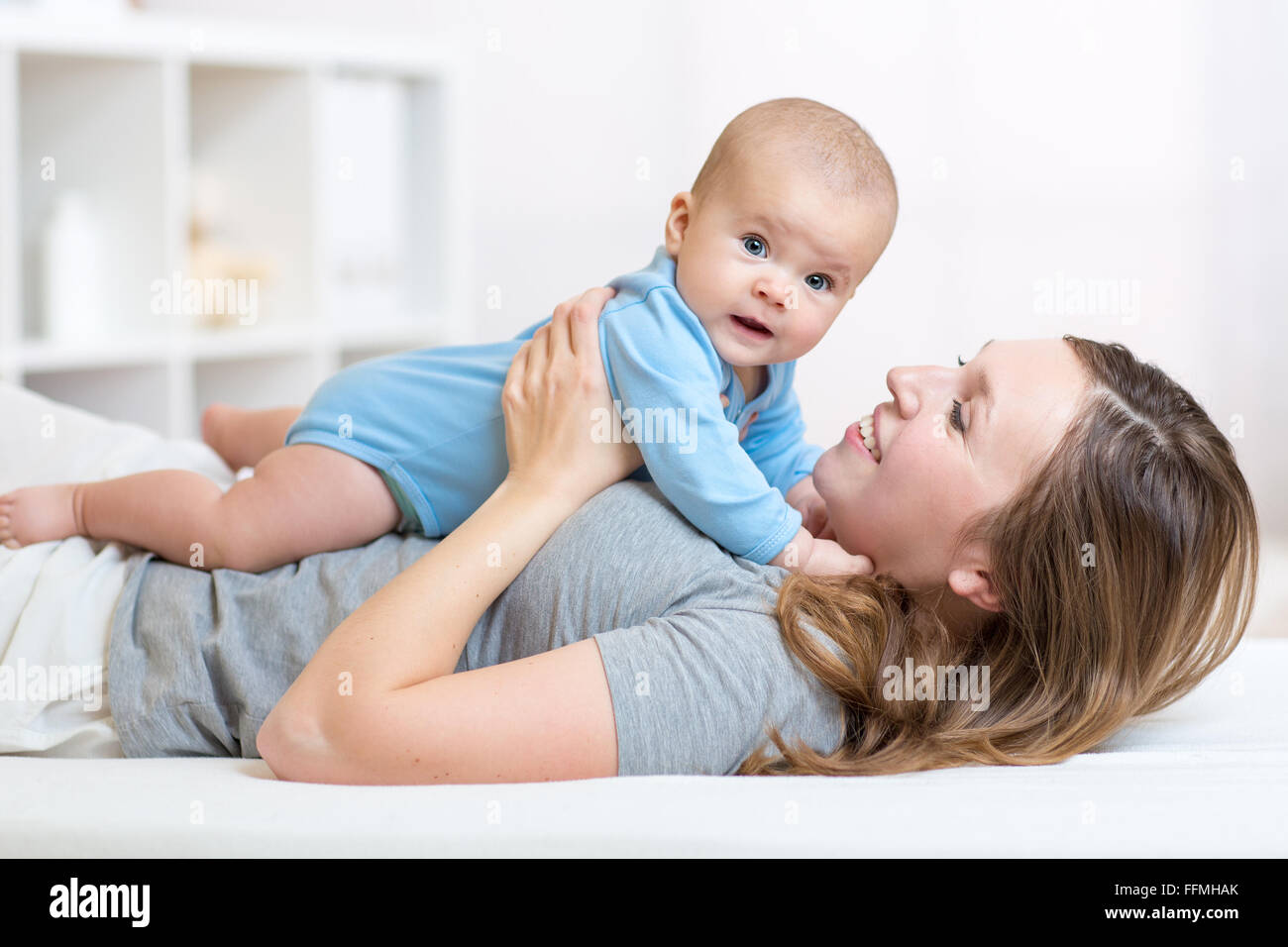 baby and smiley mother lying in bed Stock Photo