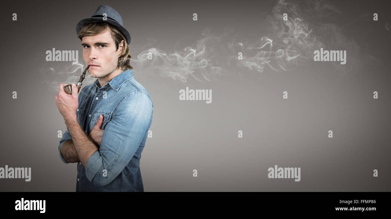 Composite image of serious hipster smoking pipe Stock Photo - Alamy