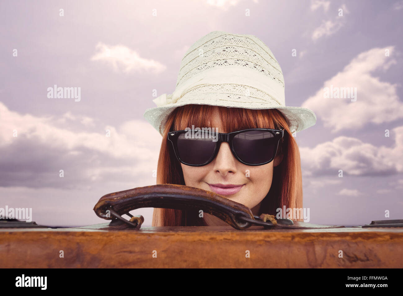 Smiling hipster woman behind a suitcase Stock Photo