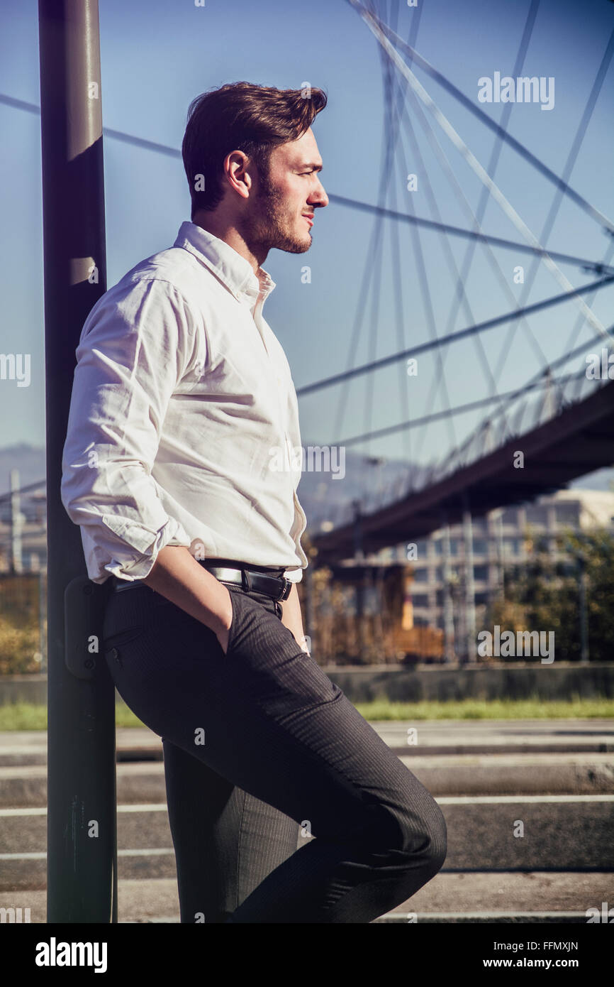 Handsome young man outside wearing white shirt, looking to a side ...