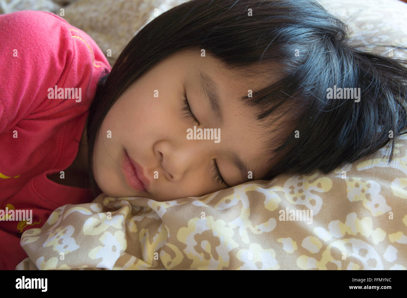 little girl sleeping on warm bed Stock Photo