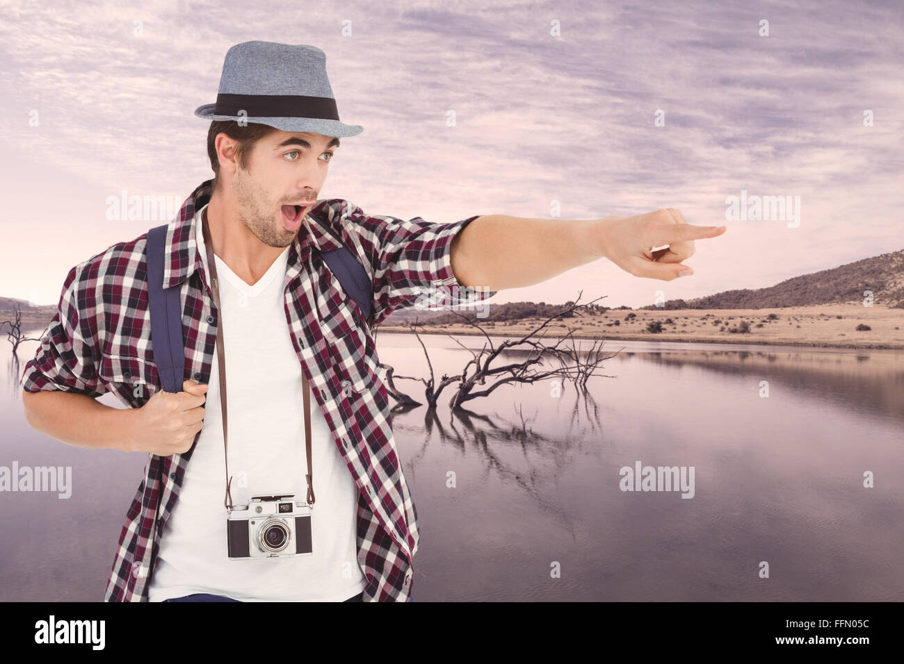 Composite image of surprised man with backpack pointing Stock Photo