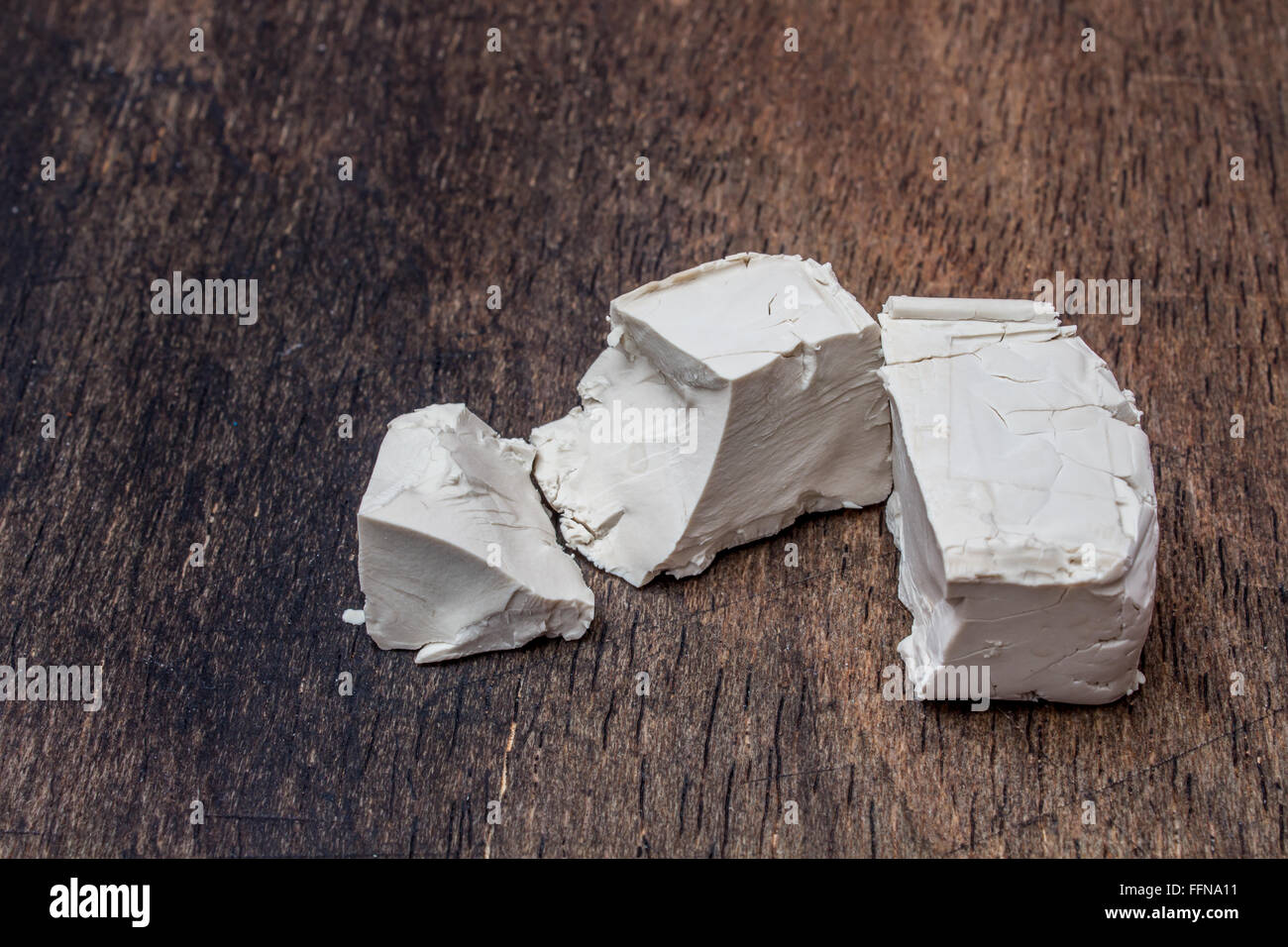 Crumbled yeast cube on a wooden kitchen table Stock Photo