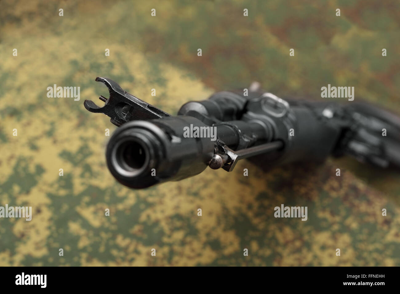 Assault rifle view from muzzle brake focus on front sight on camouflage background Stock Photo