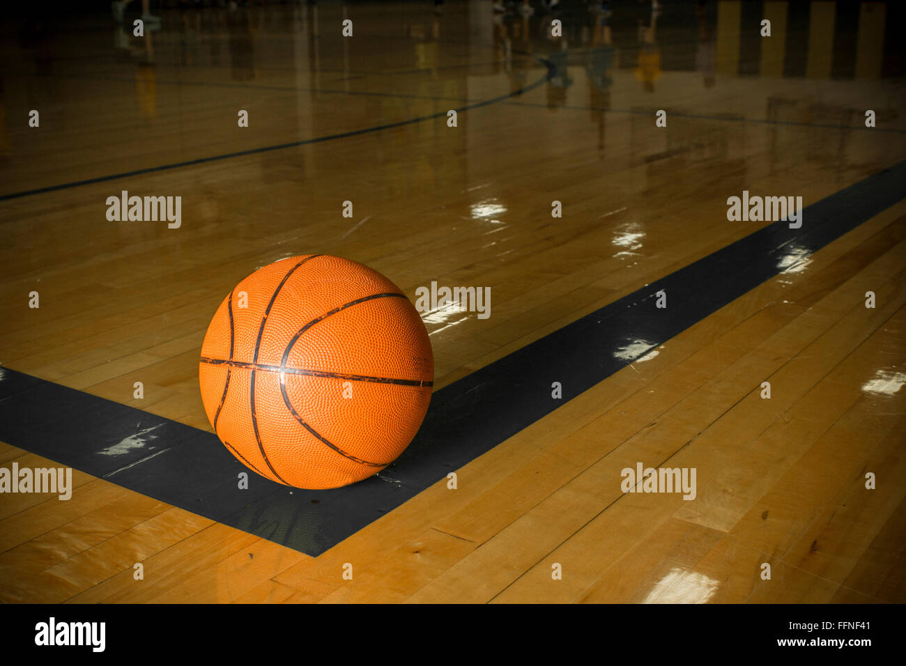 An orange basketball sitting on the corner of the boundary line of a