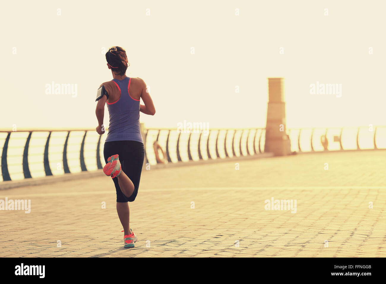 young fitness woman runner running on seaside bridge Stock Photo