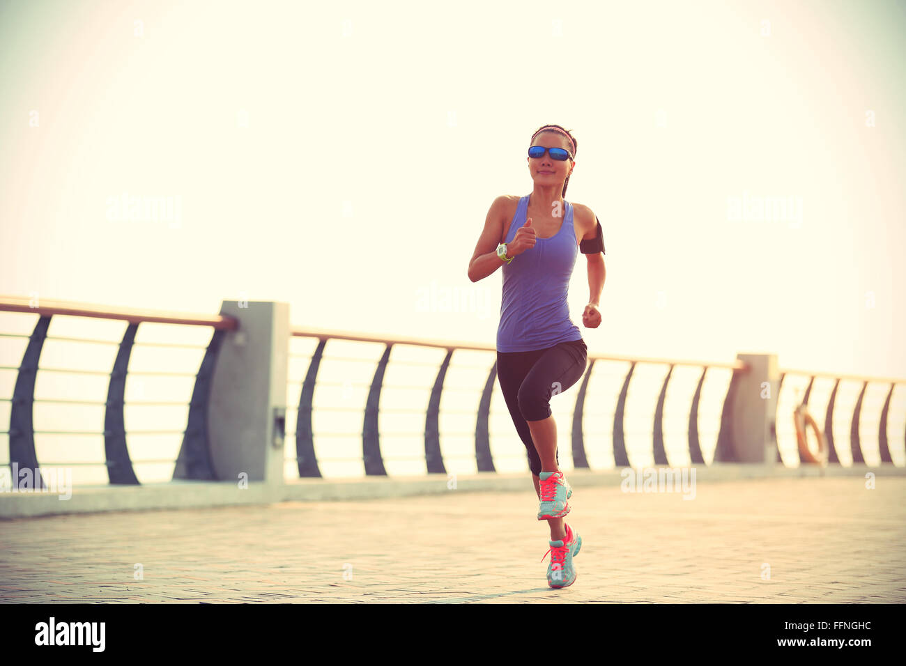 young fitness woman runner running on seaside bridge Stock Photo