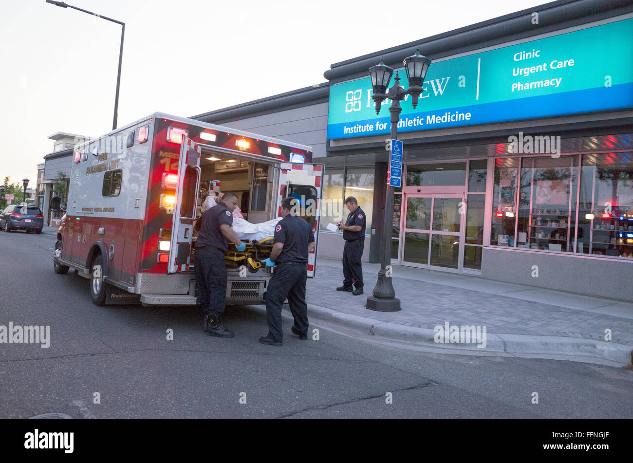 Paramedics loading victim on rolling gurney into their emergency vehicle. St Paul Minnesota MN USA Stock Photo