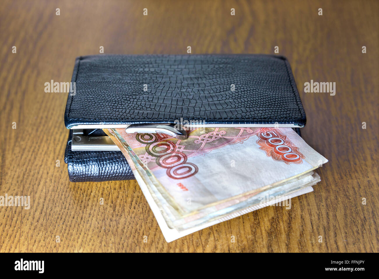 Wallet with cash lying on a wooden table Stock Photo
