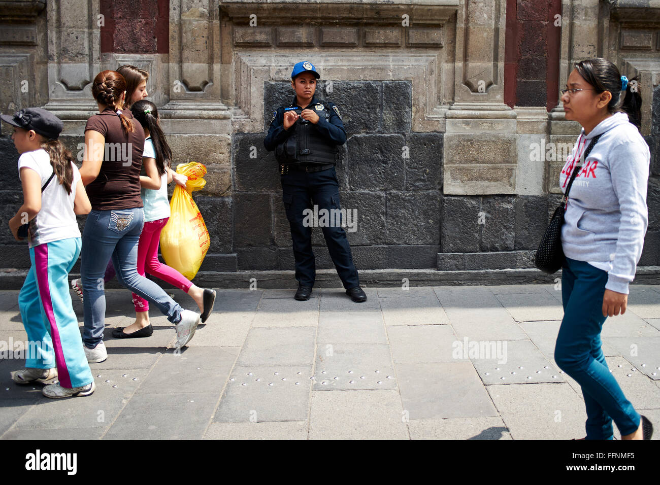 Mexican police cleans her fingernails while passersby walk past Stock Photo