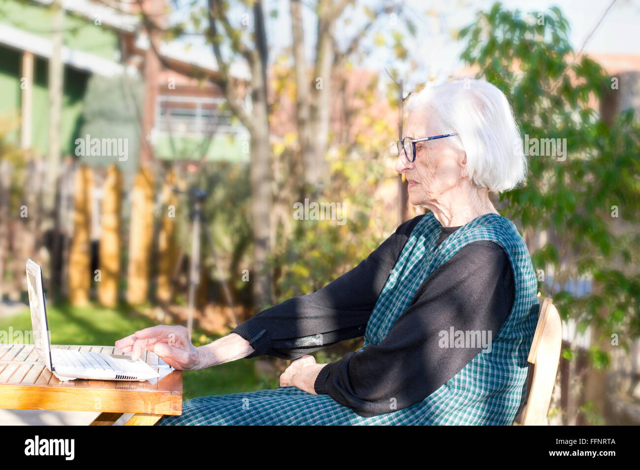 90 years old woman having a video call on a white notebook Stock Photo