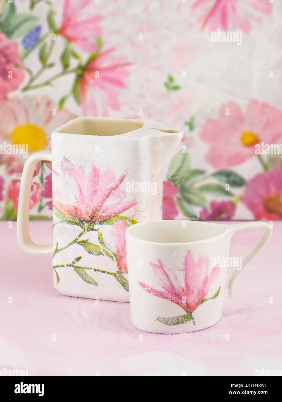 Decoupage decorated tea pot and tea cup against decoupage decorated background Stock Photo