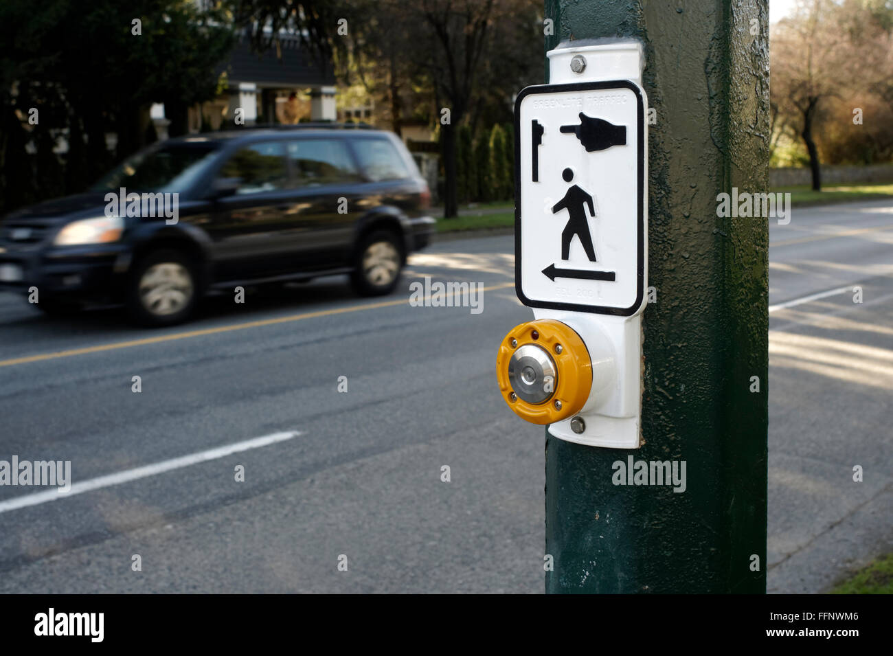Pedestrian crosswalk signal button with street an SUV in background, Vancouver, BC, Canada Stock Photo