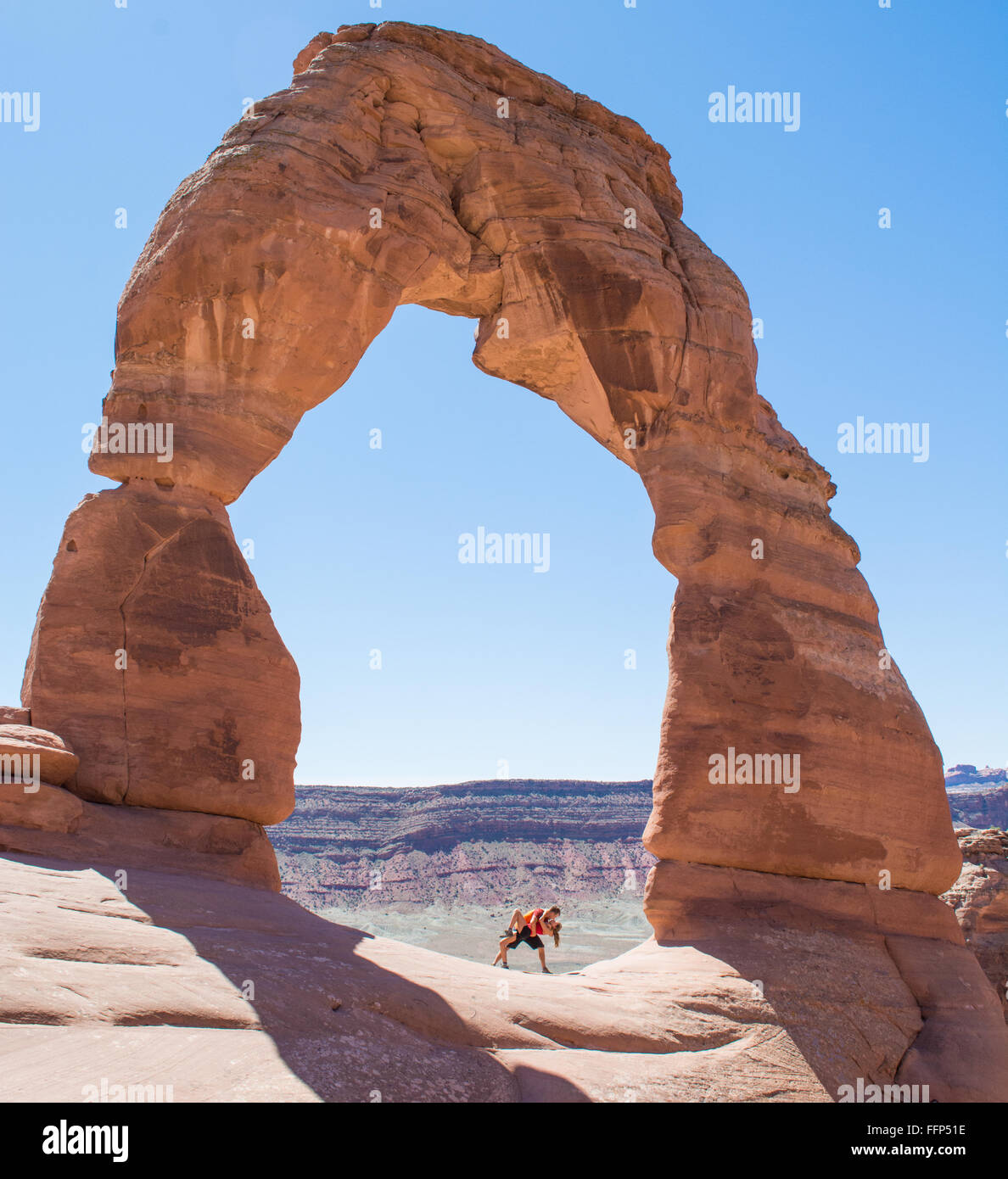 A couple kissing under Delicate Arch in  the Arches National Park Stock Photo
