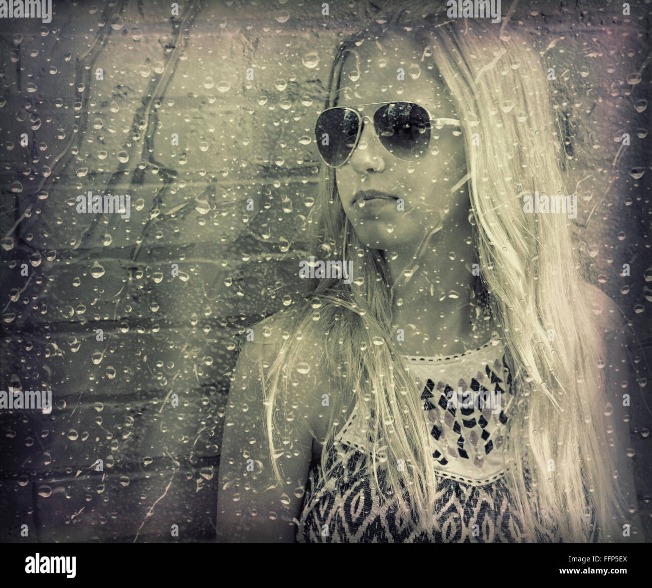 Teenage girl wearing aviator sunglasses with raindrops on window