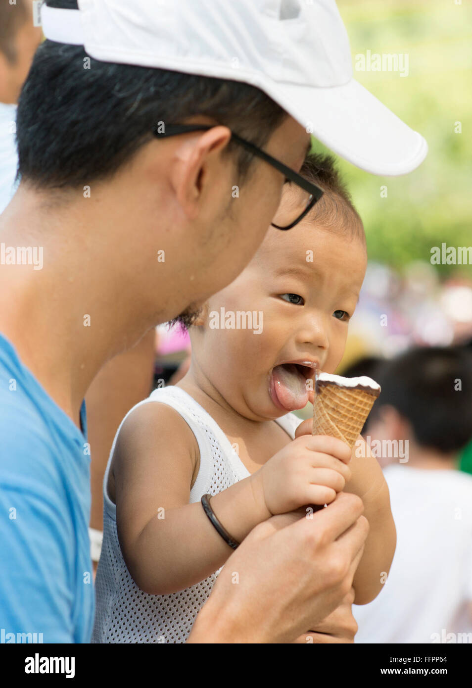 Asian father and child are eating ice creams on summer holidays. Candid family photo. Stock Photo