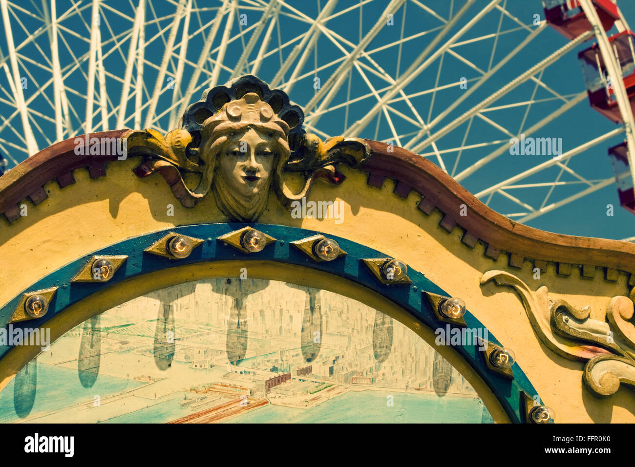 Carving of female head on old carousel with ferris wheel in background Stock Photo