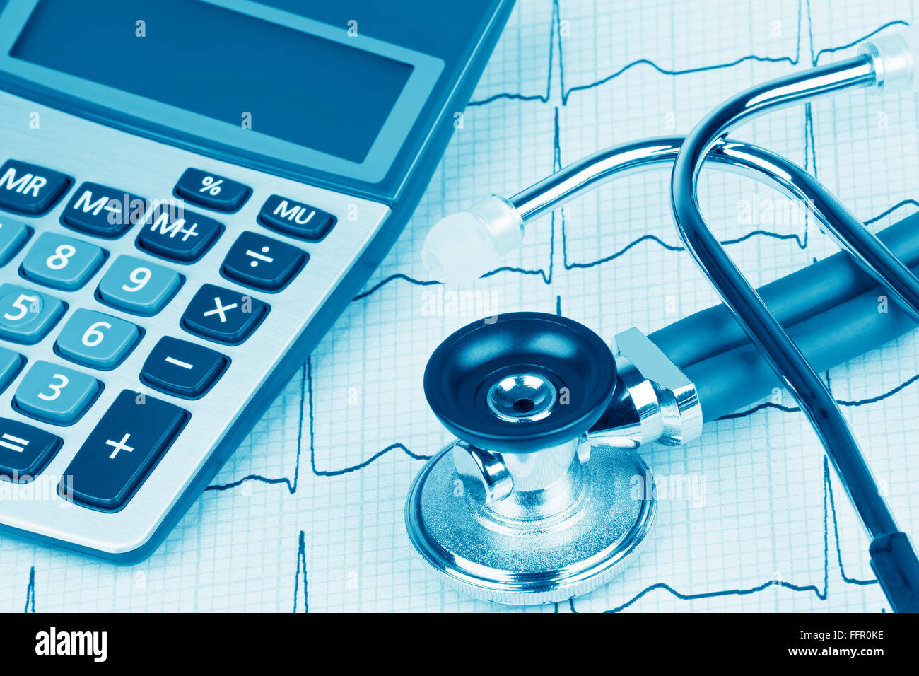 Electrocardiograph also known as a EKG or ECG graph with a stethoscope and calculator showing the high cost of heath care Stock Photo