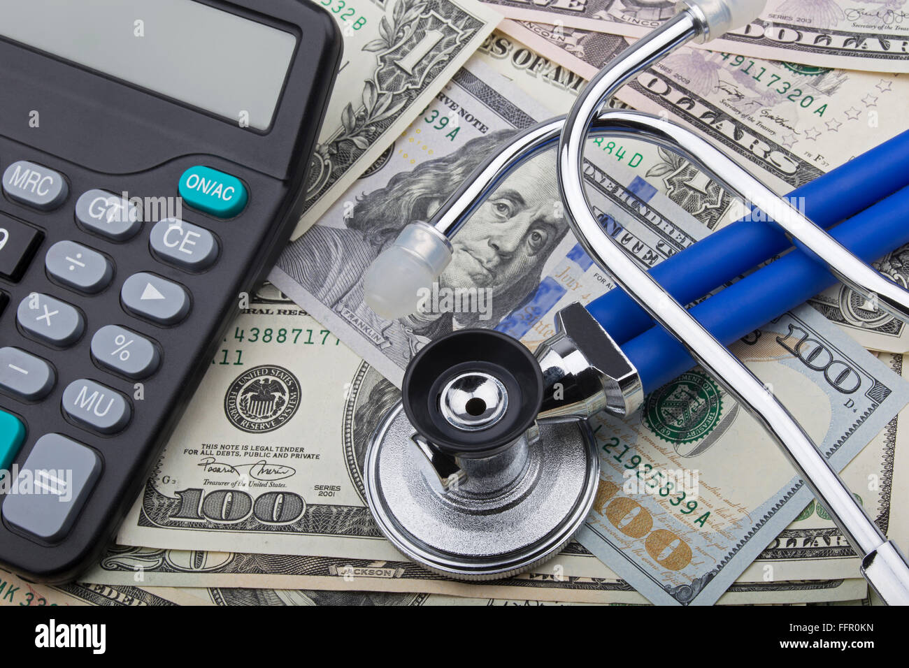 USD bank notes with a stethoscope and calculator showing the high cost of health care Stock Photo