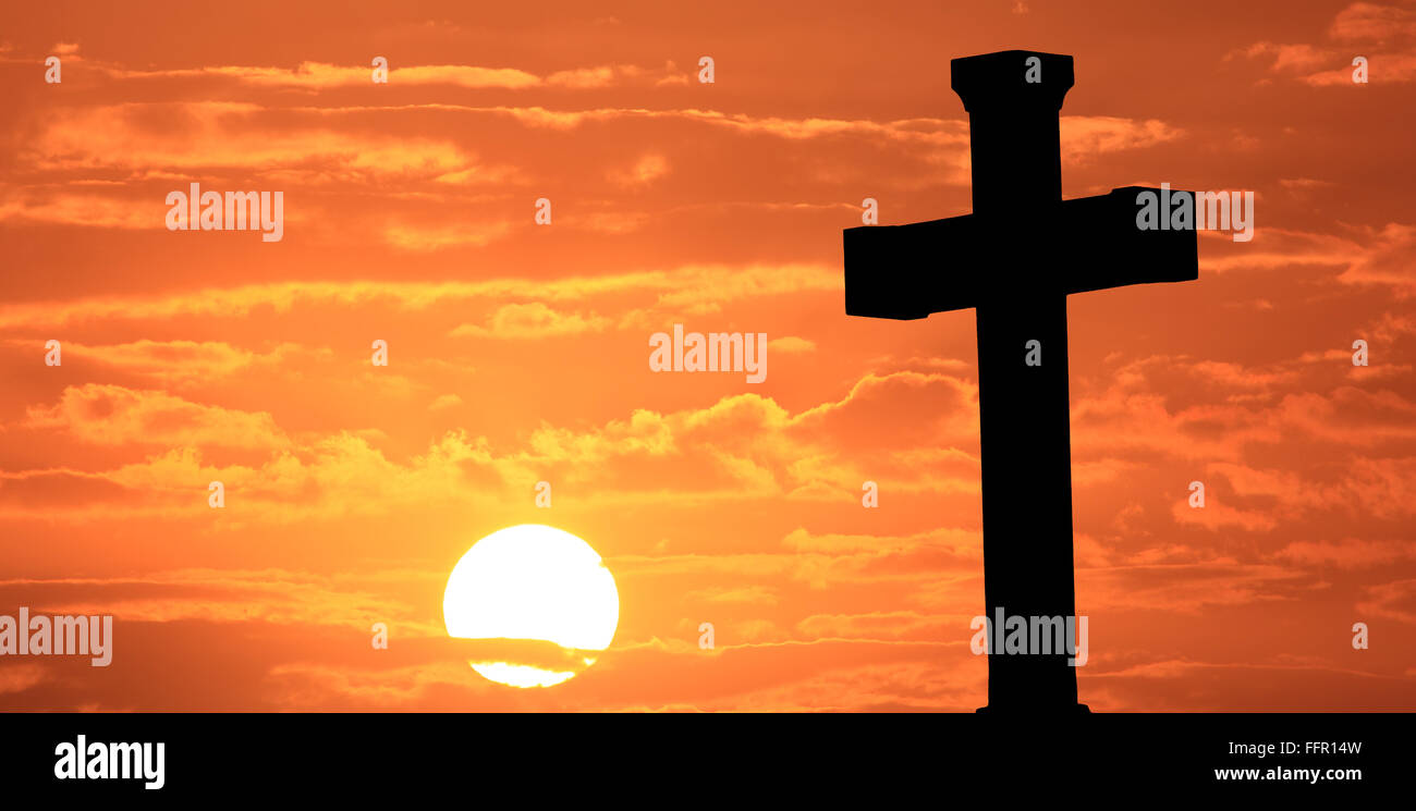 Easter cross at sunrise with orange sky and clouds. Stock Photo