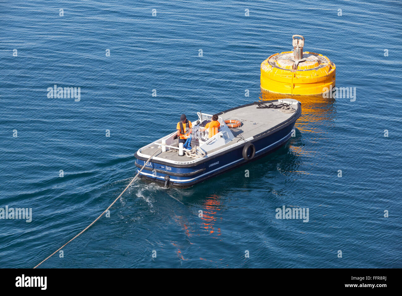 Ajaccio, France - June 30, 2015: Port operations, men at work. Motorboat is used for rope connection on yellow mooring buoy Stock Photo