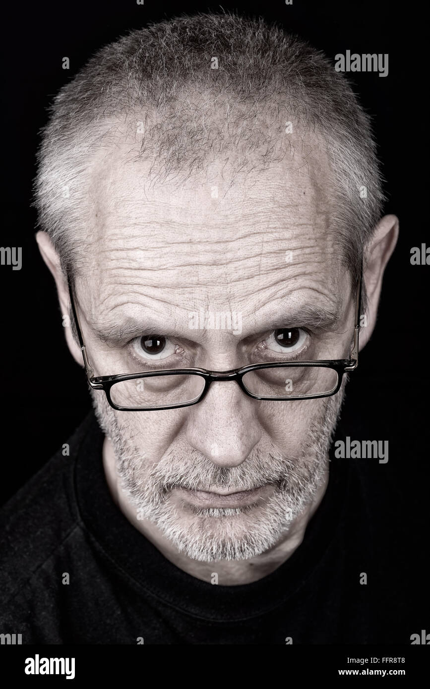 Portrait of a serious adult man wearing glasses with an inquisitive ...