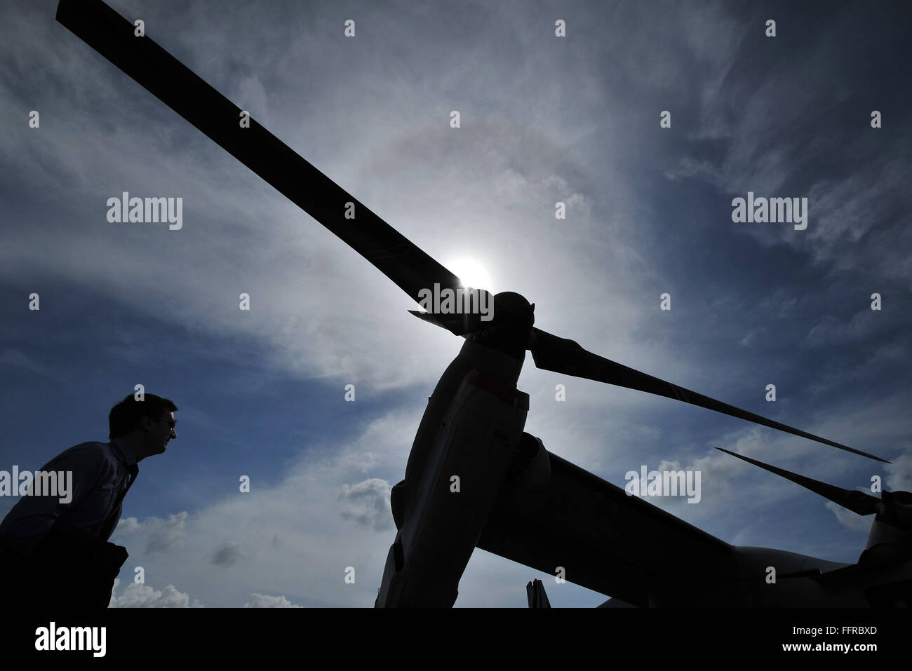 Singapore. 17th Feb, 2016. A visitor walks under one of the rotors of a V-22 Osprey tilt-rotor aircraft of the United States Air Force at the Singapore Airshow held at Singapore's Changi Exhibition Centre, Feb. 17, 2016. The Singapore Airshow, Asia's largest and one of the most important aerospace and defence exhibitions in the world, kicked off Tuesday with a renewed focus on driving global aviation industry trends and developments. Credit:  Then Chih Wey/Xinhua/Alamy Live News Stock Photo