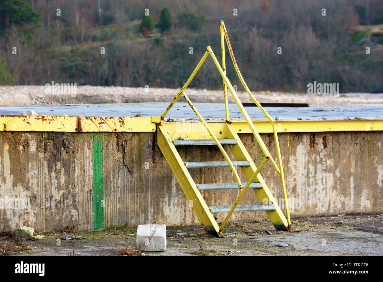Yellow metal steps leading up to a concrete foundation. Railings are ...