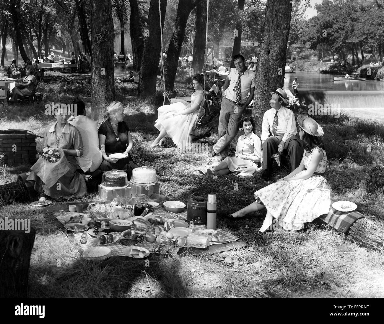 FILM: PICNIC, 1955. /nLabor Day picnic in a small town in Kansas. Scene from from the 1955 film version of Willima Inge's play 'Picnic' with Kim Novak, on swing, William Holden, standing, and Rosalind Russell, leaning against tree. Stock Photo