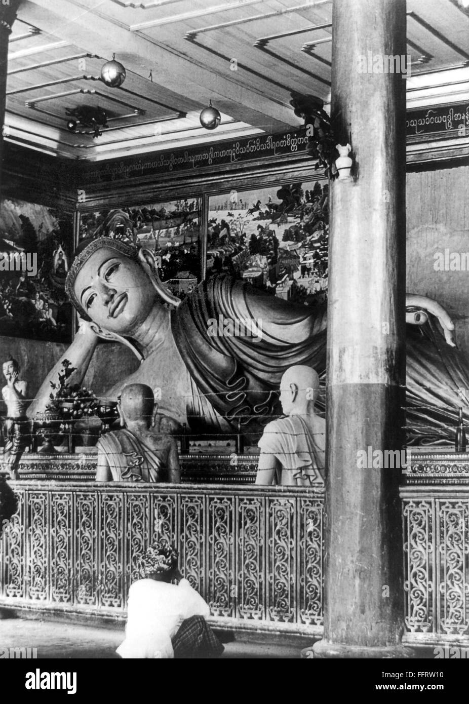 BANGKOK: BUDDHA./nA large statue of a buddha inside a temple with a worshipper seated in the foreground. Photograph, late 19th or early 20th century. Stock Photo